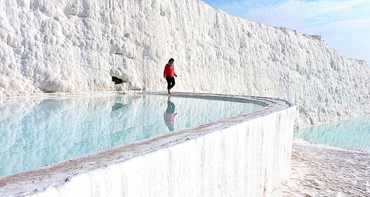 Eine Person, die entlang eines natürlichen Thermalbeckens in Pamukkale spaziert.