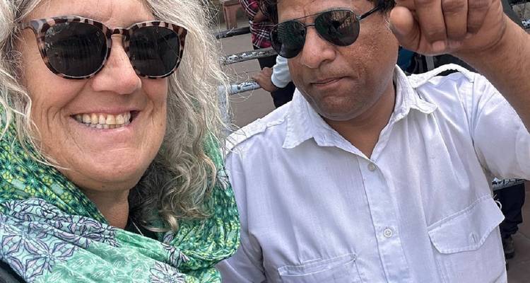 Nahaufnahme-Selfie einer lächelnden Frau in Sonnenbrille und eines Mannes, der neben ihr zeigt