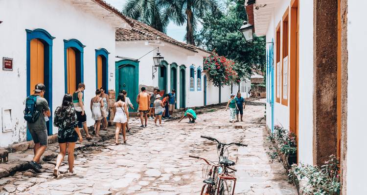 Groep toeristen die over een geplaveide straat lopen met koloniale architectuur.