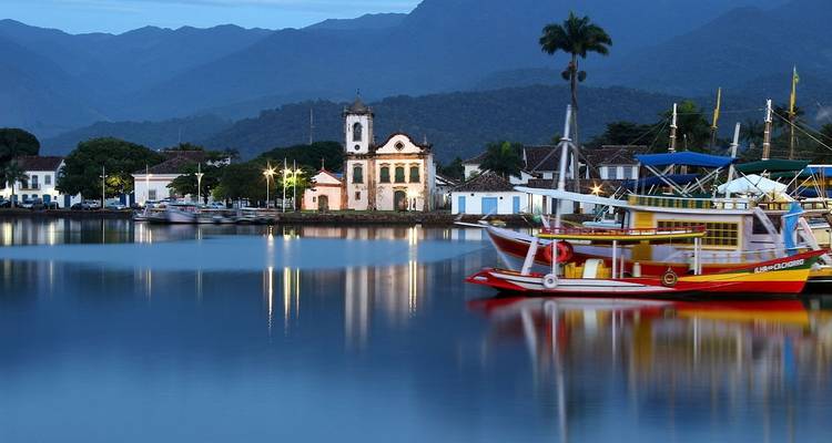 Avondhavenscène met boten en een kerk, weerkaatsend in het water.