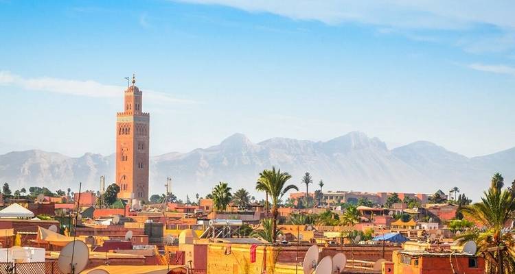 Vue panoramique avec un minaret proéminent et des montagnes au loin.