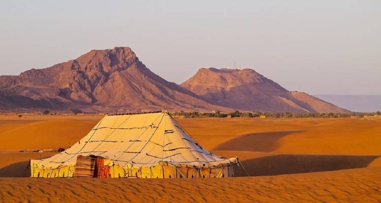 Traditionele nomadentent in een woestijnlandschap met bergen.