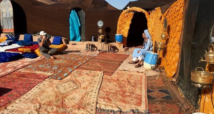 Buitenmarktscène met mensen bij traditioneel versierde tenten.