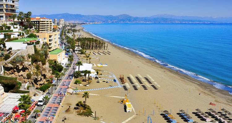 Luchtfoto van een lang zandstrand, promenade en badplaats langs Spaans's Costa del Sol op een heldere dag.