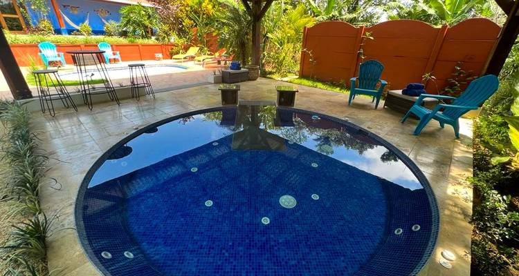 Ronde jacuzzi in een tropische buitenomgeving met ligstoelen.