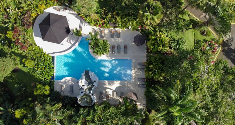 Luchtfoto van een tropisch resort met een zwembad en tuinen.