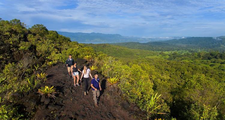 Groepswandeling over een vulkanisch rotspad met uitgestrekte bosuitkichten.