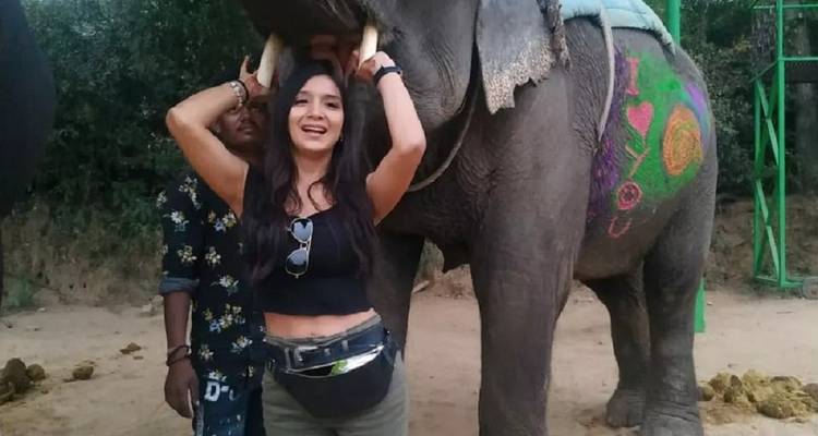Femme posant sous la trompe d'un éléphant.