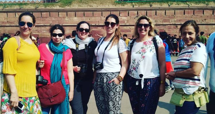 Groupe de femmes posant devant des murs historiques en grès rouge.
