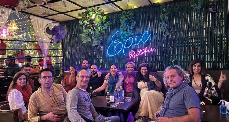 Groupe de personnes dînant sous une enseigne au néon dans un restaurant.