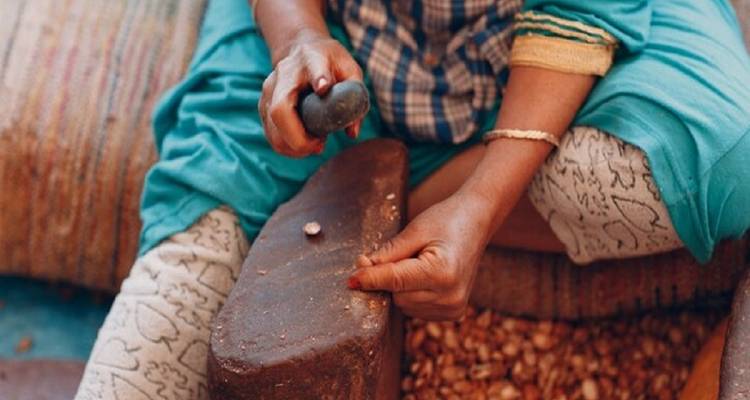 Eine Person, die Argannüsse auf einem traditionellen Stein verarbeitet.