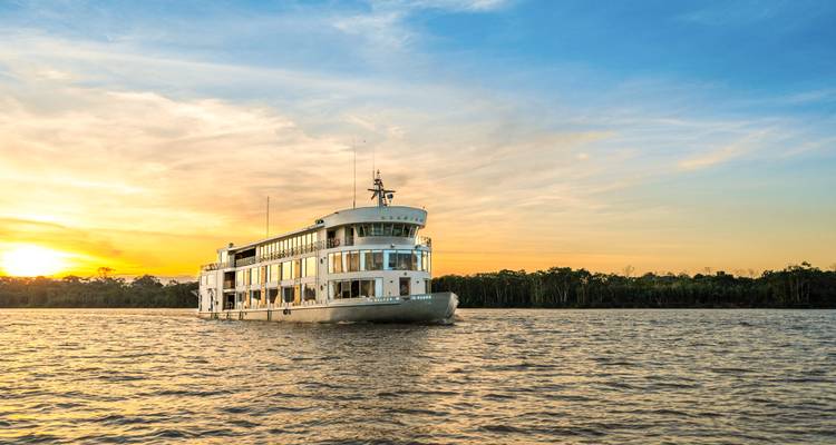 Boot varend op een rivier bij zonsondergang met een levendige lucht.