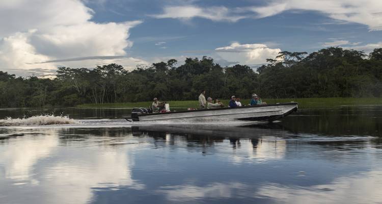 Mensen in een motorboot op een rivier met een jungle achtergrond.