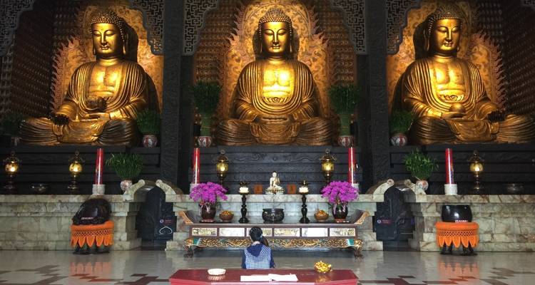 Drie grote gouden Boeddhabeelden in een tempel.