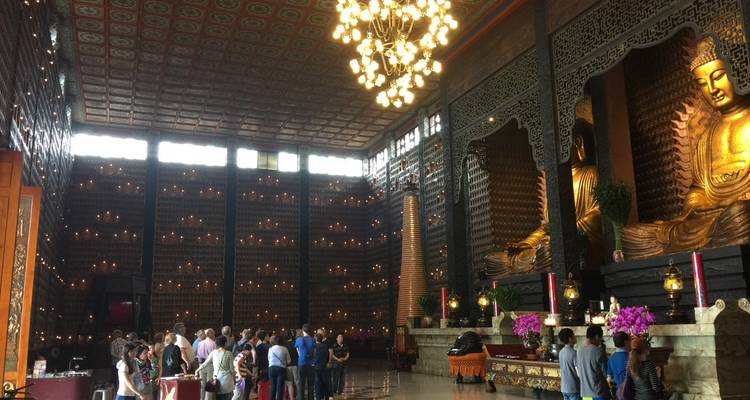 Interieur van een tempel met bezoekers en groot Boeddhabeeld.