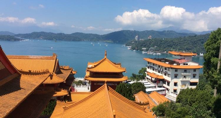 Uitzicht op Sun Moon Lake met traditionele daken en schilderachtige bergachtergrond.