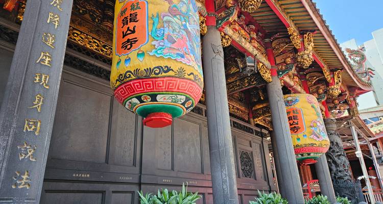 Lanternes rouge vif et dorées suspendues à l'extérieur du temple Longshan mettant en valeur les sculptures sur bois complexes