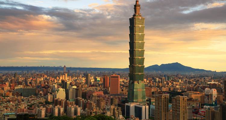 Taipei 101 dominant dans l'horizon urbain durant un coucher de soleil coloré avec des montagnes au loin