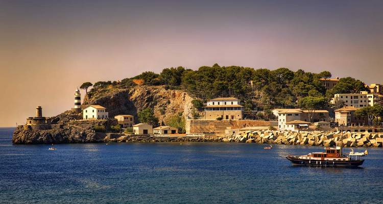 Vista panorámica de un pueblo costero con faro y barcos.
