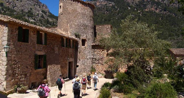 Turistas explorando una estructura histórica de piedra con montañas de fondo.