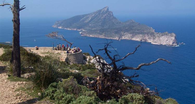Vista panorámica de un paisaje costero con personas disfrutando de la vista y una isla distante.