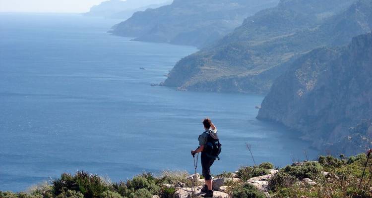 Wanderer, der über eine dramatische Klippen-Aussicht aufs Meer blickt.