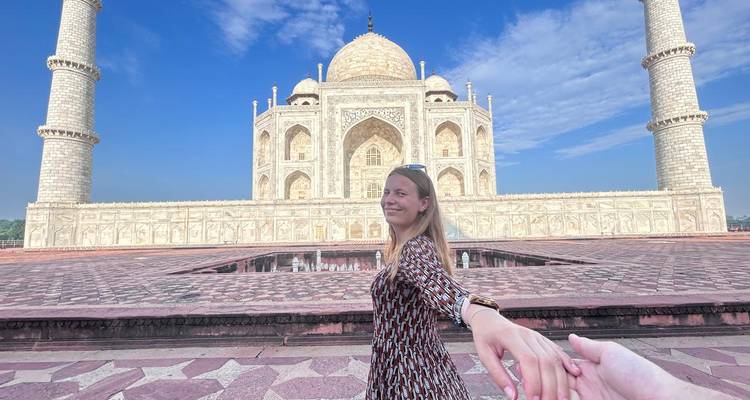 Frau hält Hand mit Partner vor dem Taj Mahal.