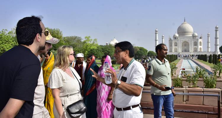Reiseführer spricht mit Touristen vor dem Taj Mahal im Hintergrund.