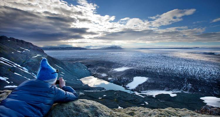 Person, die einen riesigen Gletscher von einem hohen Aussichtspunkt aus fotografiert.