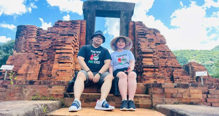 Dos personas sentadas frente a estructuras antiguas de ladrillo.