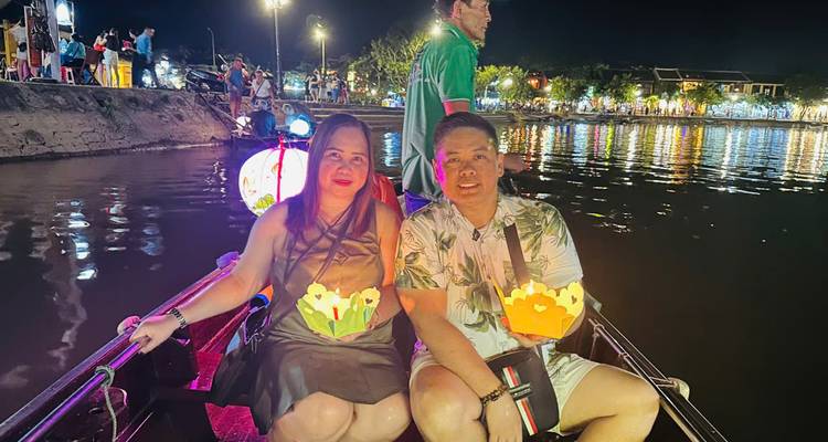 Pareja en un barco por la noche, sosteniendo linternas flotantes.