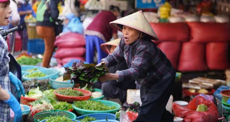 vendedor sosteniendo hierbas frescas en un mercado local bullicioso con canastas tejidas de productos
