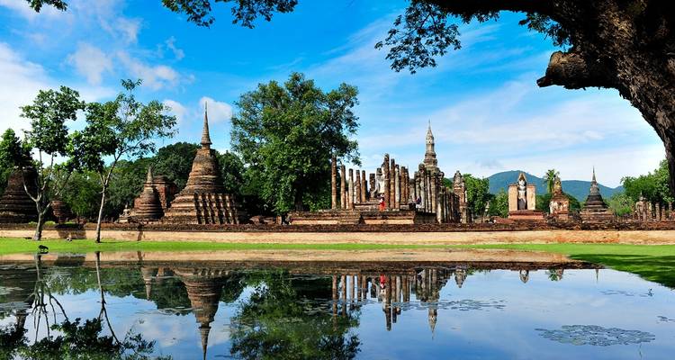 Antike Ruinen mit Stupas, die sich im Wasser spiegeln.