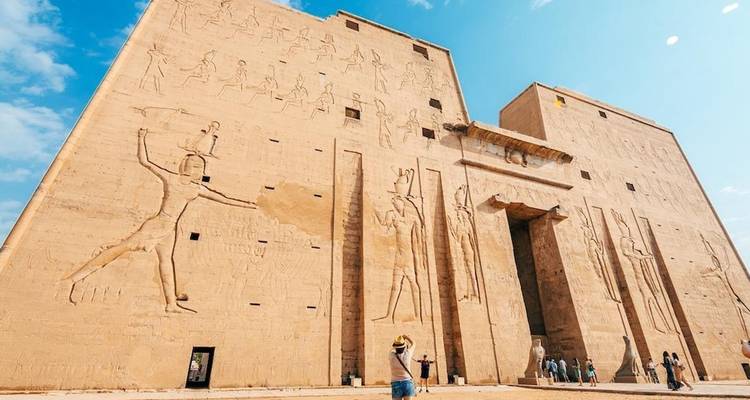 A temple facade with relief carvings under a bright blue sky.