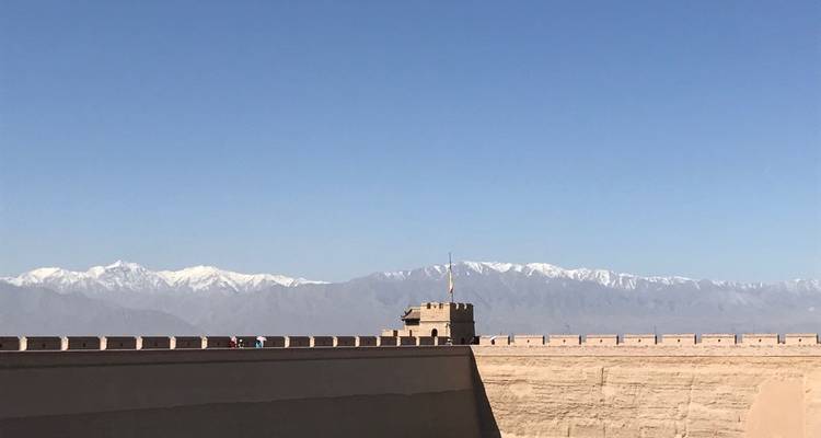 Muur van een fort met besneeuwde bergen op de achtergrond.