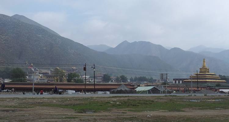 Dorp met bergen en een gouden pagode in de verte.