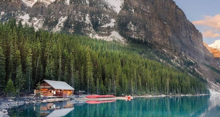 Picturesque mountain lake with a log cabin and red canoe in Canada.
