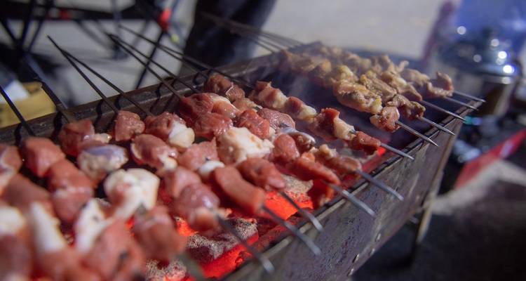 Skewers of meat grilling over hot coals.