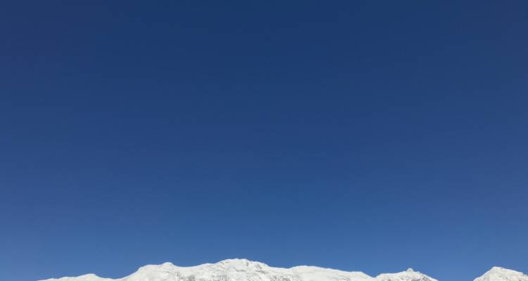 White snowy mountain peaks against a deep blue sky.