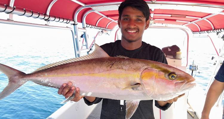 Mann, der einen großen Fisch auf einem Boot auf dem Wasser hält.