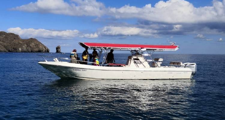Boot mit Menschen an Bord segelt in ruhigen Gewässern.