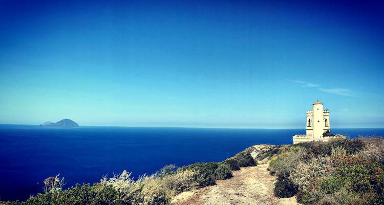 Coastal landscape with a small tower and distant islands.