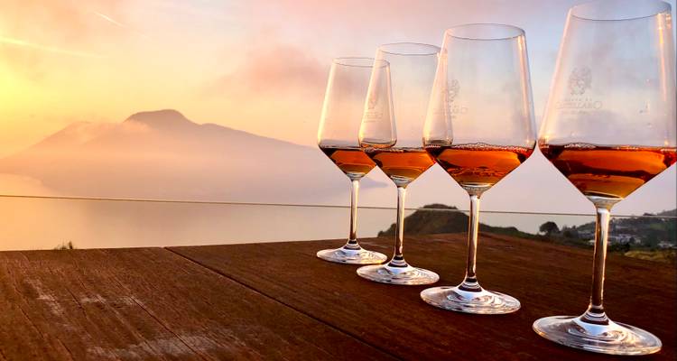 Four wine glasses with a scenic sunset view.