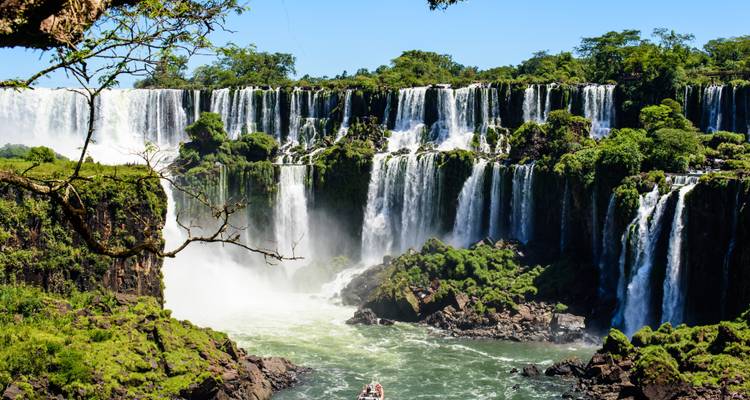 Majestic waterfalls with a boat navigating the water below.