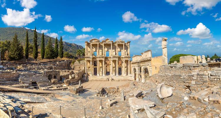 Vue panoramique de l'ancienne bibliothèque de Celse et des ruines environnantes sous un ciel bleu éclatant.