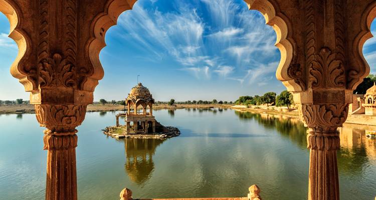 Vista a través de arcos ornamentados hacia un cenotafio en un lago en Jaisalmer.