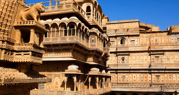 Las fachadas de arenisca dorada y balcones del Fuerte de Jaisalmer brillando bajo un cielo azul despejado.