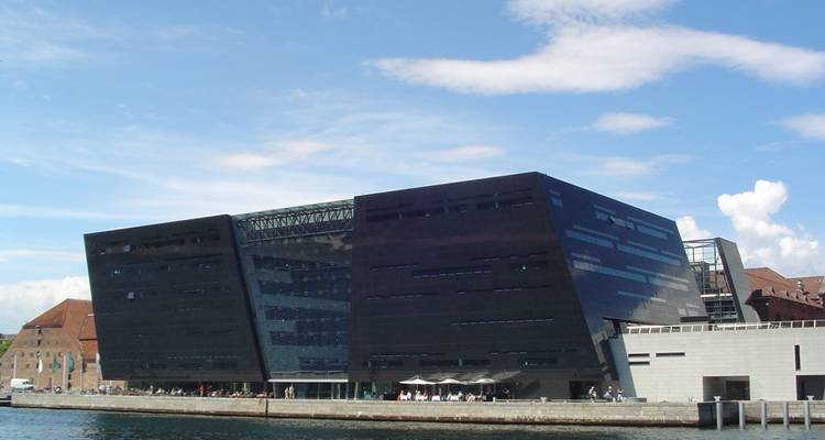 Bâtiment moderne en verre noir au bord de l'eau.