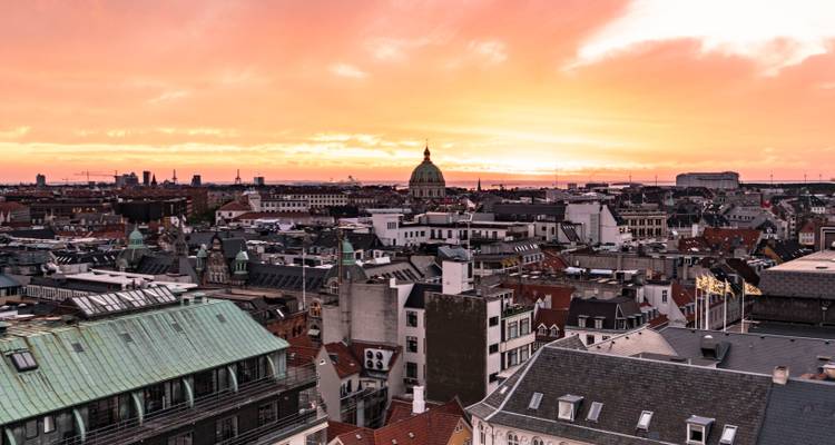 Vue aérienne de Copenhague au coucher du soleil avec le dôme de l'église Frederik visible.