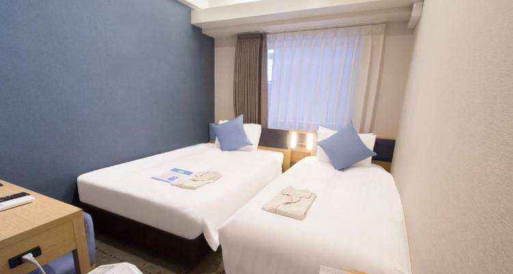 Hotelzimmer mit zwei Einzelbetten und einem hellblauen Farbschema.